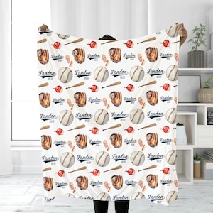 May include: White baby blanket with a repeating pattern of baseballs, bats, gloves, popcorn, and hot dogs. The text "Landon Reid" is repeated throughout the pattern.