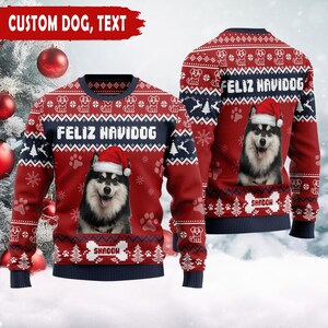 May include: Red Christmas sweater with a dog wearing a Santa hat. The sweater has the text "FELIZ NAVIDOG" and "SHADOW". The top of the sweater has a pattern of snowflakes, dogs, and Christmas trees. The sleeves and bottom hem are navy blue.