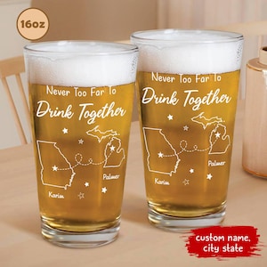May include: Two 16-ounce personalized beer glasses with a white design. The design features two states connected by a dotted line with the text "Never Too Far To Drink Together".