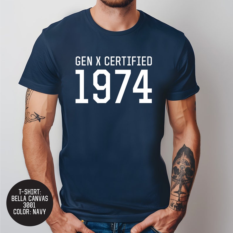 Pu&ograve; includere: Una t-shirt blu navy con testo bianco che recita "GEN X CERTIFIED 1974".