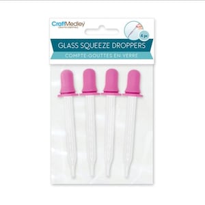 Puede incluir: Cuatro cuentagotas de vidrio con tapas rosas, empaquetados en una bolsa de plástico transparente. El paquete tiene el texto "GLASS SQUEEZE DROPPERS" y "COMPTE-GOUTTES EN VERRE". La marca "CraftMedley" también es visible.