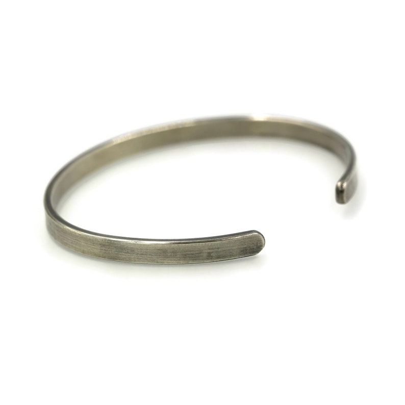 Puede incluir: Una pulsera de pu&ntilde;o de color plateado con un acabado de metal cepillado. El dise&ntilde;o abierto permite un f&aacute;cil uso. La pulsera es un accesorio simple y minimalista.