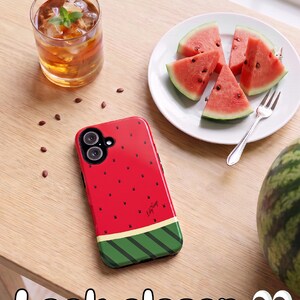 以下が含まれることがあります： スイカをモチーフにした赤と緑のスマートフォンケース。小さな黒いウサギのシルエットが散りばめられ、黒いカメラハウジングと、赤い部分の右下に黒い筆記体でLily Neigeという文字がプリントされています。