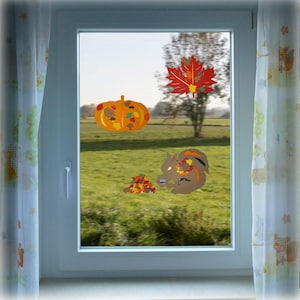 Könnte beinhalten: Ein Fenster mit Herbstdekorationen, darunter ein Kürbis, ein Eichhörnchen und ein rotes Ahornblatt. Die Dekorationen sind aus Papier und mit Klebeband am Fenster befestigt.
