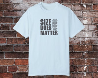 Könnte beinhalten: Hellblaues T-Shirt mit einer schwarzen Grafik eines Kameraobjektivs und dem Text "SIZE DOES MATTER".