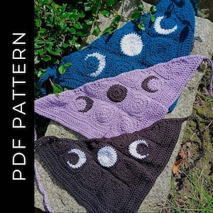 Puede incluir: Tres chales triangulares de ganchillo con diseños de luna y media luna. Los chales son de color negro, morado y azul.