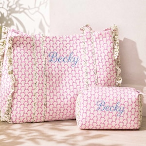 Peut inclure: Un sac fourre-tout rectangulaire et une pochette assortie plus petite, tous deux dotés d'un motif répétitif rose et blanc et d'une bordure à volants floraux. Le prénom Becky est brodé en bleu sur le devant des deux articles à deux anses.