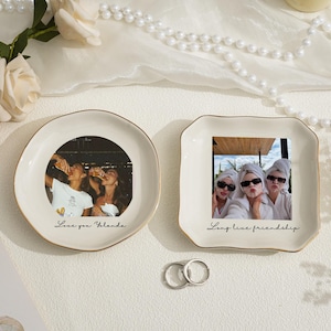 May include: Two decorative ceramic dishes with gold rims. One round dish features a photo of people drinking, with the text "Love you Yolanda." The other square dish has a photo of three people, with the text "Long live friendship."