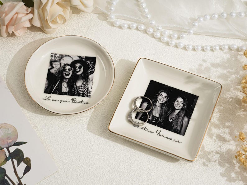 May include: Two ceramic trinket dishes with gold trim. One is round, the other square. Each features a black and white photo of smiling women. The round dish says "Love you Bestie", the square dish says "Bestie Forever".