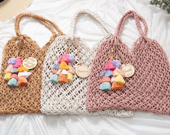 Può includere: Tre borse a rete in crochet con etichette in legno. Le borse sono marrone, bianca e rosa. Ogni borsa ha un fiocco colorato attaccato. Le etichette hanno i nomi "Alice", "Bernice" e "Camille" scritti su di esse.