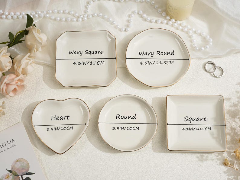 May include: A collection of small, white ceramic dishes in various shapes: wavy square (4.3 inches/11 cm), wavy round (4.5 inches/11.5 cm), heart (3.9 inches/10 cm), round (3.9 inches/10 cm), and square (4.1 inches/10.5 cm). Each dish has a gold rim.