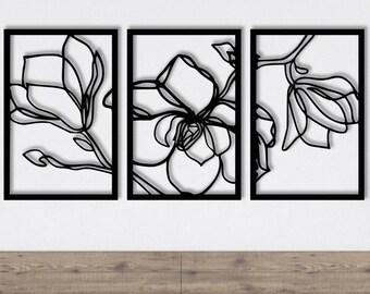 May include: Three black metal wall art pieces featuring a stylized floral design. The art is displayed on a white wall above a wooden headboard and a bed with a light blue duvet.