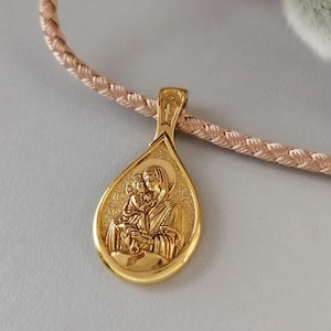Puede incluir: Collar de oro con un colgante en forma de lágrima que presenta una imagen religiosa de la Virgen María y el niño Jesús.