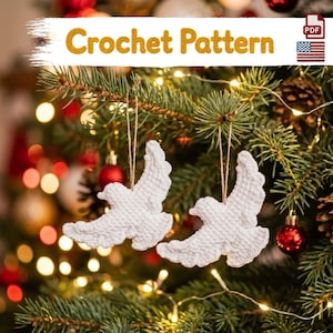 May include: A digital PDF crochet pattern for two white bird ornaments with outstretched wings, each hanging from a thin string. The text Crochet Pattern is displayed at the top of the image, accompanied by a small United States flag icon.