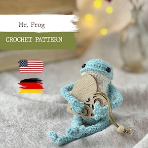 Puede incluir: Patrón de crochet para una rana azul que sostiene un corazón de madera. El patrón está disponible en inglés y alemán. Mr. Frog Crochet Pattern.