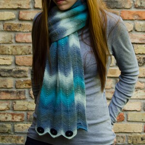 Peut inclure: Une écharpe rayée bleu et blanche avec un détail de bouton unique. L'écharpe est faite d'un tissu doux et tricoté et est parfaite pour ajouter une touche de couleur à n'importe quelle tenue.