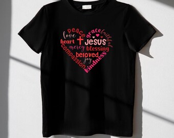 May include: Black t-shirt with a pink and red heart design featuring the words "peace", "grace", "faithful", "love", "heart", "Jesus", "mercy", "blessing", "beloved", "joy", "compassion", and "kindness".