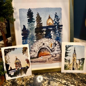 May include: Three watercolor paintings of buildings in a forest setting. The first painting shows a building with a golden dome, the second shows a stone archway, and the third shows a church with a tall steeple.