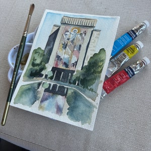 May include: Watercolor painting of a building with a large mural on the side. The mural depicts a religious scene with figures in white and gold. The painting is on a white background and is surrounded by green trees.