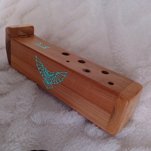 Op de afbeelding: Een houten ocarina met een lichtbruine afwerking. Het instrument heeft een geometrisch uilontwerp en symbolen in turquoise. De ocarina heeft verschillende vingergaten en een mondstuk. Ongeveer 25 cm lang.