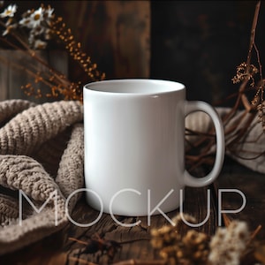 Puede incluir: Taza de cerámica blanca con asa, sobre una superficie de madera rústica con flores secas y una bufanda de punto.
