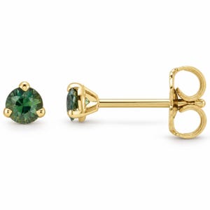 May include: A pair of stud earrings featuring round-cut, deep green gemstones set in polished yellow gold. One earring is shown from the front, while the other is displayed from the side, revealing the gold post and the secure butterfly earring back.
