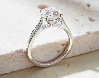 May include: A silver engagement ring with a large, round, clear diamond.