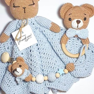 Puede incluir: Juego de bebé tejido a crochet en azul claro, que incluye una manta con cabeza de oso de peluche, un mordedor de oso de peluche con un anillo de madera y un clip para chupete con un oso de peluche. El set tiene una etiqueta que dice "¡Gracias!"