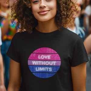 May include: A black t-shirt with a circular design in pink, purple, and blue, featuring the text "LOVE WITHOUT LIMITS." The image is set against a backdrop of rainbow flags and people.
