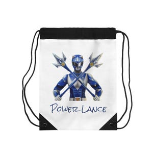 May include: White drawstring backpack featuring a blue Power Ranger with crossed weapons. The Power Ranger is in a blue and white suit, holding two silver and gold lances. The text "POWER LANCE" is written in blue script below the image. The top and drawstring are black.