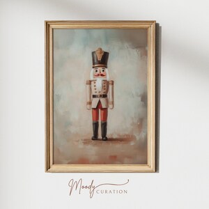 May include: A framed painting of a nutcracker soldier in a red and white uniform with a gold hat. The background is a light brown and blue watercolor wash.