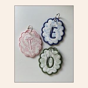 Chaveiro personalizado com laço bordado e detalhe ondulado com inicial