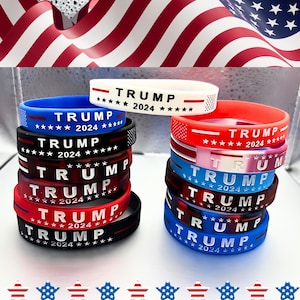 May include: A stack of colorful silicone wristbands with the text "TRUMP 2024" printed on each band. The bands are arranged in a stack of six, with the top band being white and the bottom band being blue.