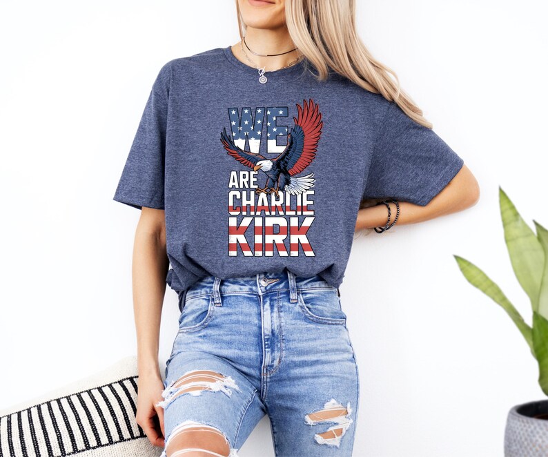 Puede incluir: Una camiseta azul marino con un gr&aacute;fico de un &aacute;guila con alas rojas, blancas y azules y el texto "WE ARE CHARLIE KIRK". La camiseta est&aacute; hecha de un material suave y es adecuada para ropa casual.