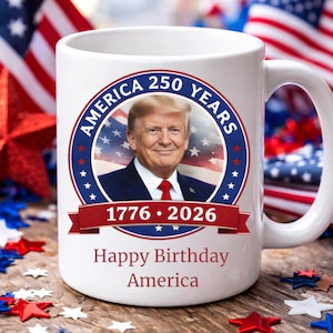 May include: White ceramic mug featuring a portrait of a man in a suit and tie, surrounded by a patriotic design. The mug includes the text "America 250 Years" and "1776-2026", with the words "Happy Birthday America" at the bottom.