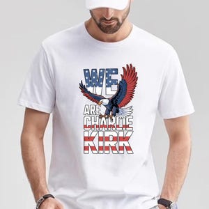 Puede incluir: Camiseta blanca con un dise&ntilde;o gr&aacute;fico de un &aacute;guila con alas rojas, blancas y azules y el texto "WE ARE CHARLIE KIRK". El &aacute;guila est&aacute; en vuelo, con las alas extendidas. El texto es en negrita y patri&oacute;tico.