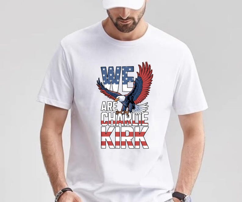 Puede incluir: Camiseta blanca con un dise&ntilde;o gr&aacute;fico de un &aacute;guila con alas rojas, blancas y azules y el texto "WE ARE CHARLIE KIRK". El &aacute;guila est&aacute; en vuelo, con las alas extendidas. El texto es en negrita y patri&oacute;tico.
