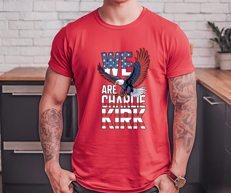 Puede incluir: Camiseta roja con un &aacute;guila calva americana y el texto "WE ARE CHARLIE KIRK". Las palabras son en blanco y azul, con la palabra "WE" dise&ntilde;ada con estrellas y rayas, que recuerdan la bandera estadounidense.