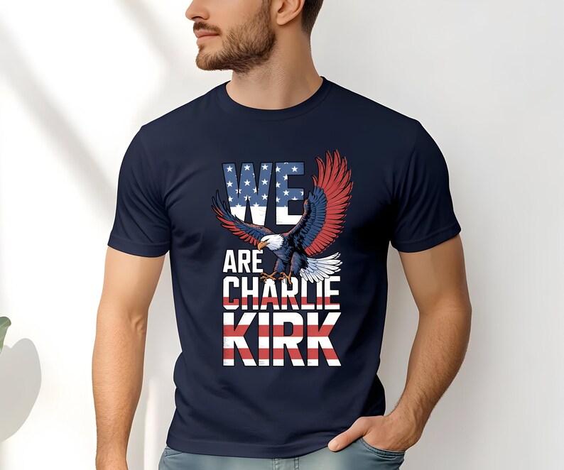 Puede incluir: Camiseta azul marino con un &aacute;guila calva americana y el texto "WE ARE CHARLIE KIRK". El texto incorpora los colores de la bandera estadounidense. Las alas del &aacute;guila son rojas y azules.