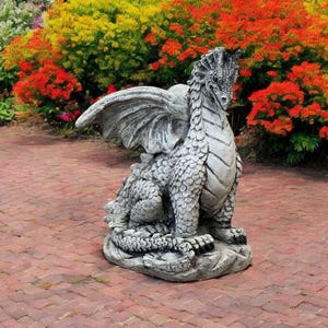 May include: A gray stone dragon statue with wings and a long tail. The dragon is sitting on a brick patio with a flower garden in the background.