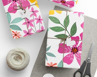 May include: Three gift boxes wrapped in white paper with pink, green, and yellow floral patterns. The boxes are tied with twine and have white paper tags attached.