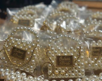 Puede incluir: Conjunto de pulseras y collares de perlas blancas y doradas, algunos empaquetados en plástico transparente. Algunas bolsas tienen una etiqueta dorada con la inscripción "Sultan's Bride".