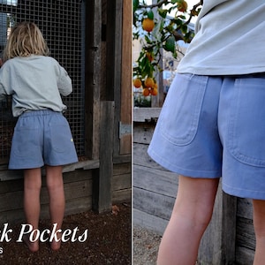 May include: Light blue shorts featuring an elastic waistband and two large patch pockets on the back. The shorts are made of a solid-colored fabric and include a small rectangular tag on the side seam of the right pocket. The design is simple.