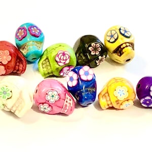 May include: A collection of ten colorful skull beads with floral designs. The beads are made of ceramic and have a glossy finish. The colors include red, white, green, blue, yellow, and purple.