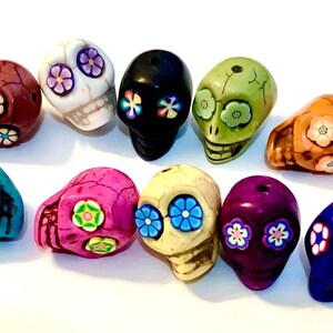 May include: Ten colorful skull beads with floral designs. The beads are made of ceramic and have a variety of colors, including turquoise, pink, purple, green, and white.
