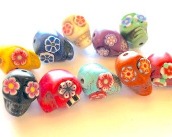 May include: Ten colorful sugar skull beads with floral designs. The beads are made of ceramic and have a glossy finish. The colors include yellow, blue, white, purple, green, red, orange, black, and turquoise.