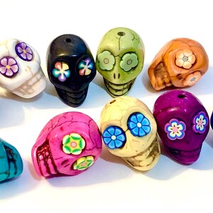 May include: Ten colorful sugar skull beads with floral designs. The beads are made of ceramic and are approximately 1 inch in diameter.