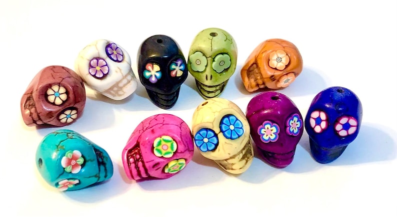 May include: Ten colorful sugar skull beads with floral designs. The beads are made of ceramic and are approximately 1 inch in diameter.