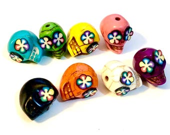 May include: Assortment of colorful skull beads with flower designs. The beads are made of plastic and are approximately 1 inch in diameter.