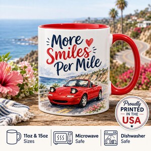 May include: A white ceramic mug with a red interior and handle, featuring a watercolour illustration of a red convertible car on a coastal road. The text reads More Smiles Per Mile with a small red heart. A circular badge states Proudly Printed In The USA.